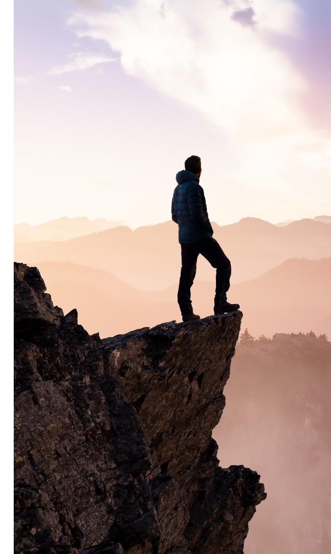 Personne en haut d'une montagne regardant l'horizon.